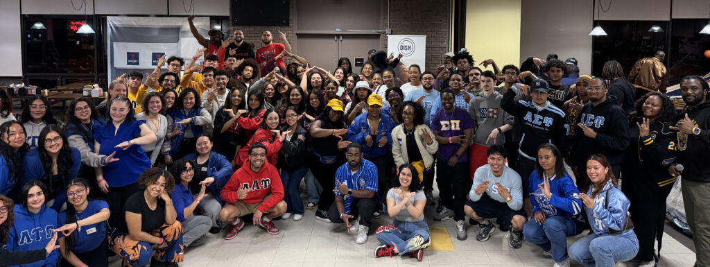 A big group of smiling sorority and fraternity members at a Greek Showcase event.