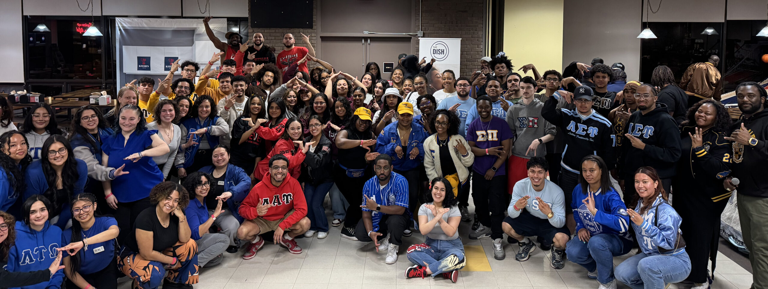A big group of smiling sorority and fraternity members at a Greek Showcase event.