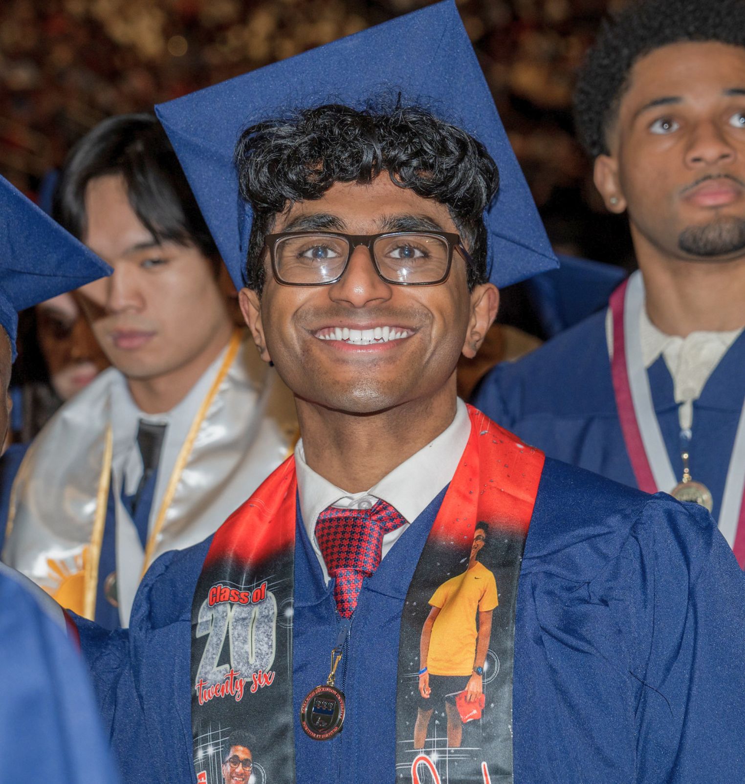 a graduating student smiles at the camera. he wears a cap and gown.