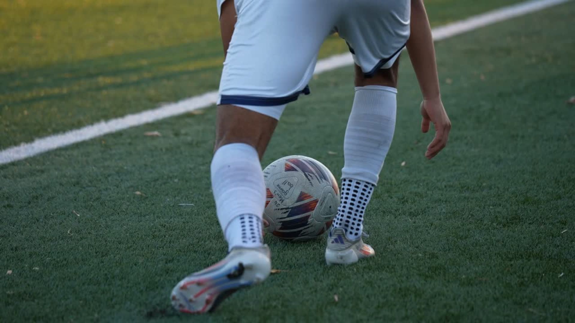 a close-up shot of the feet of a soccer player kicking a soccer ball.