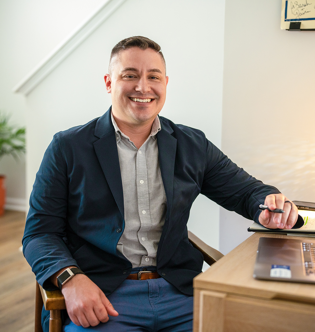 A man sits at a desk with an open laptop.