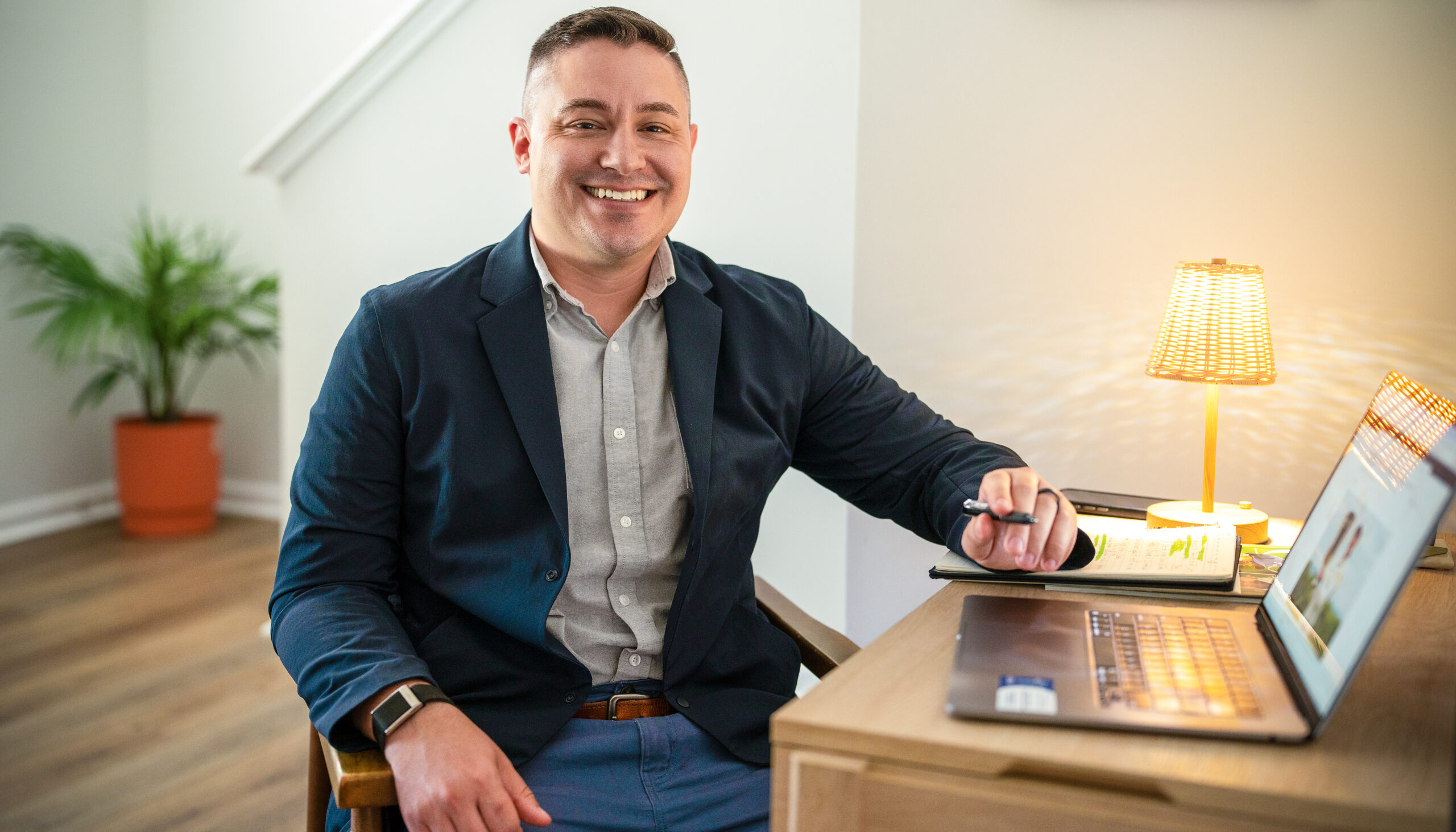 A man sits at a desk with an open laptop.
