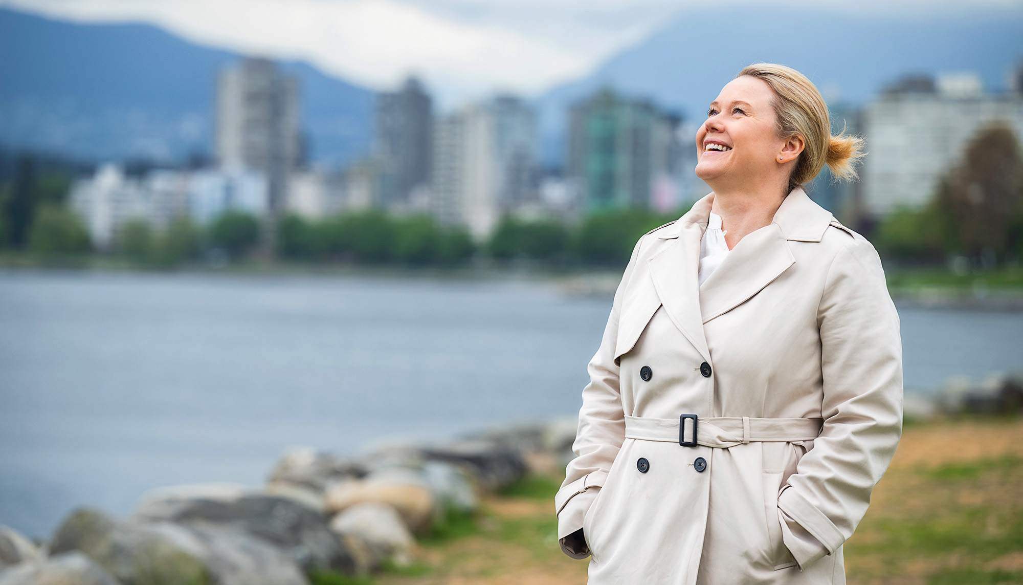 A woman wearing a trench coat takes in her surroundings in British Columbia, Canada.