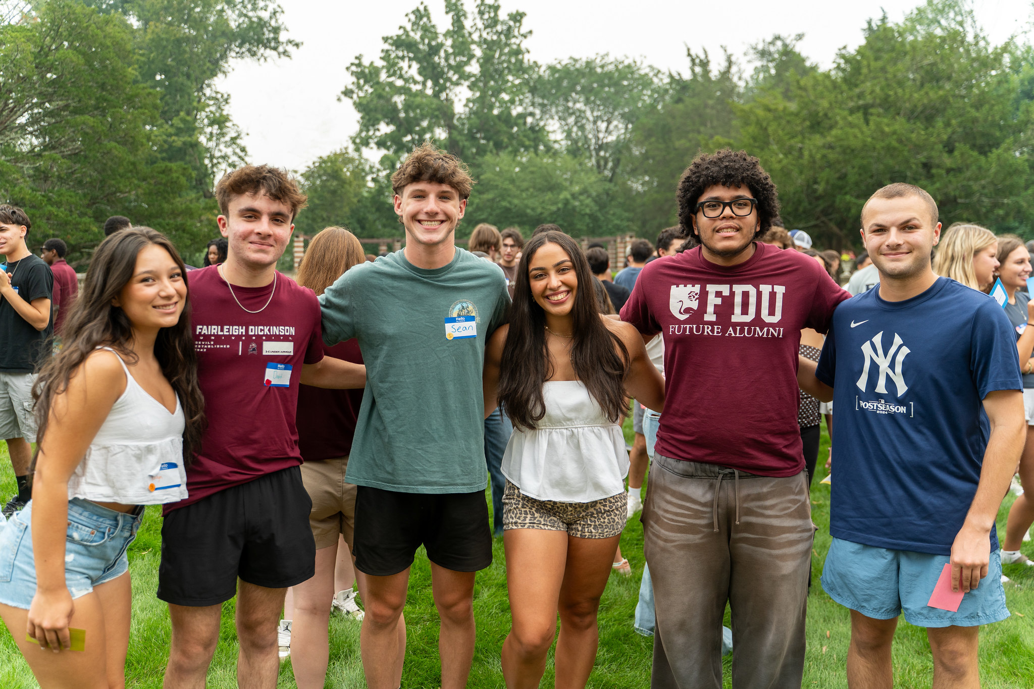a group of college students smile for the camera. two of the students wear FDU shirts.