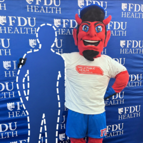 A red devil mascot character stands in front of a blue backdrop featuring repeated 