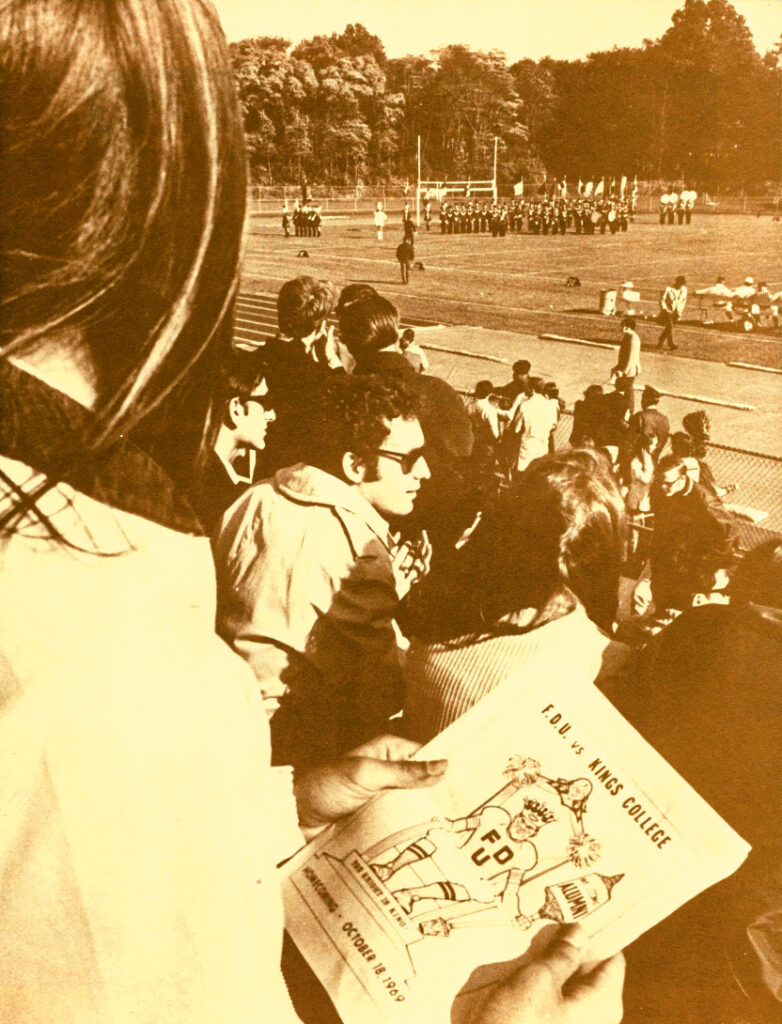 Students sit in the stands to watch a football game.