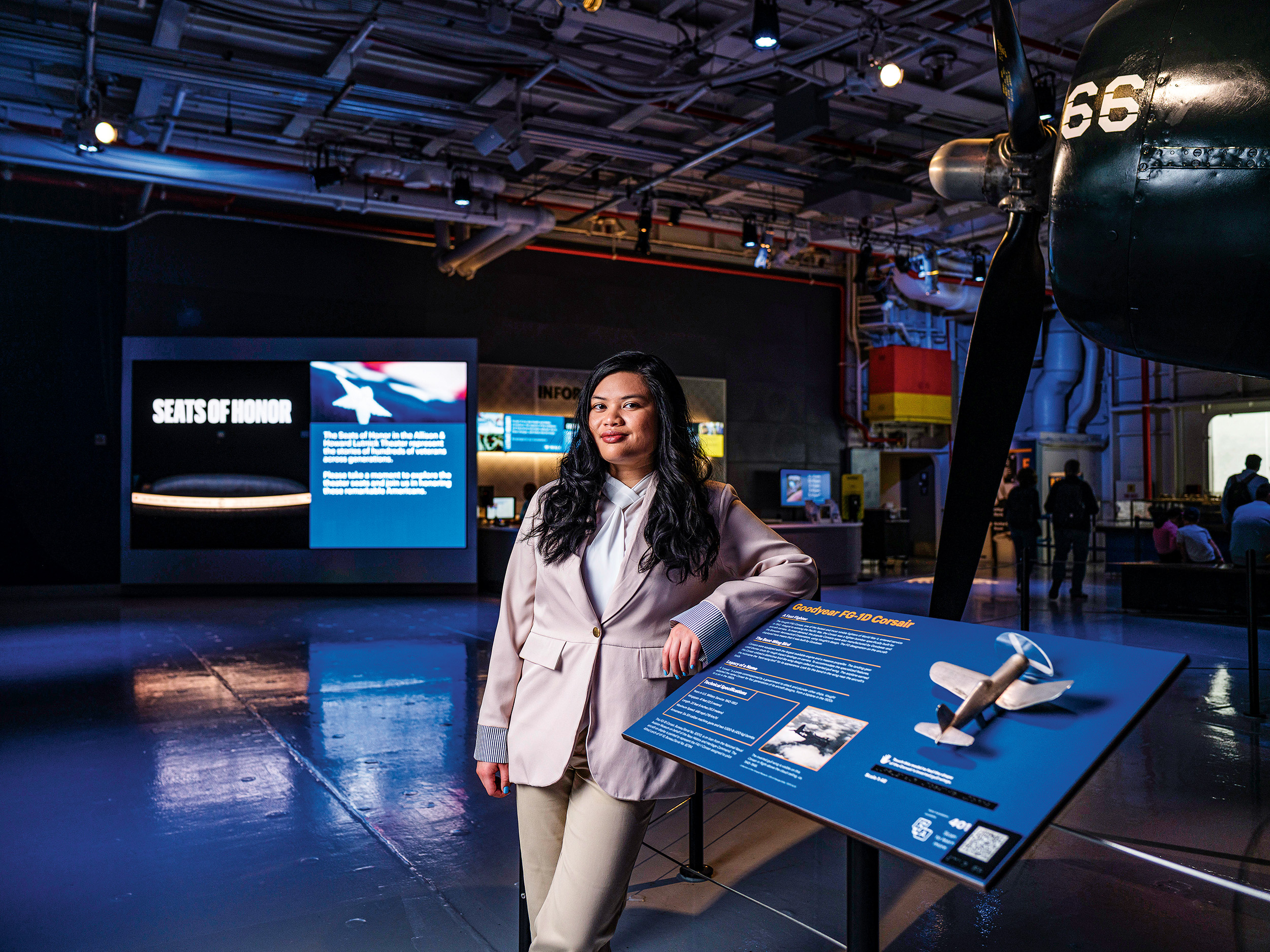 A woman wearing a suit poses for a photo in a museum.