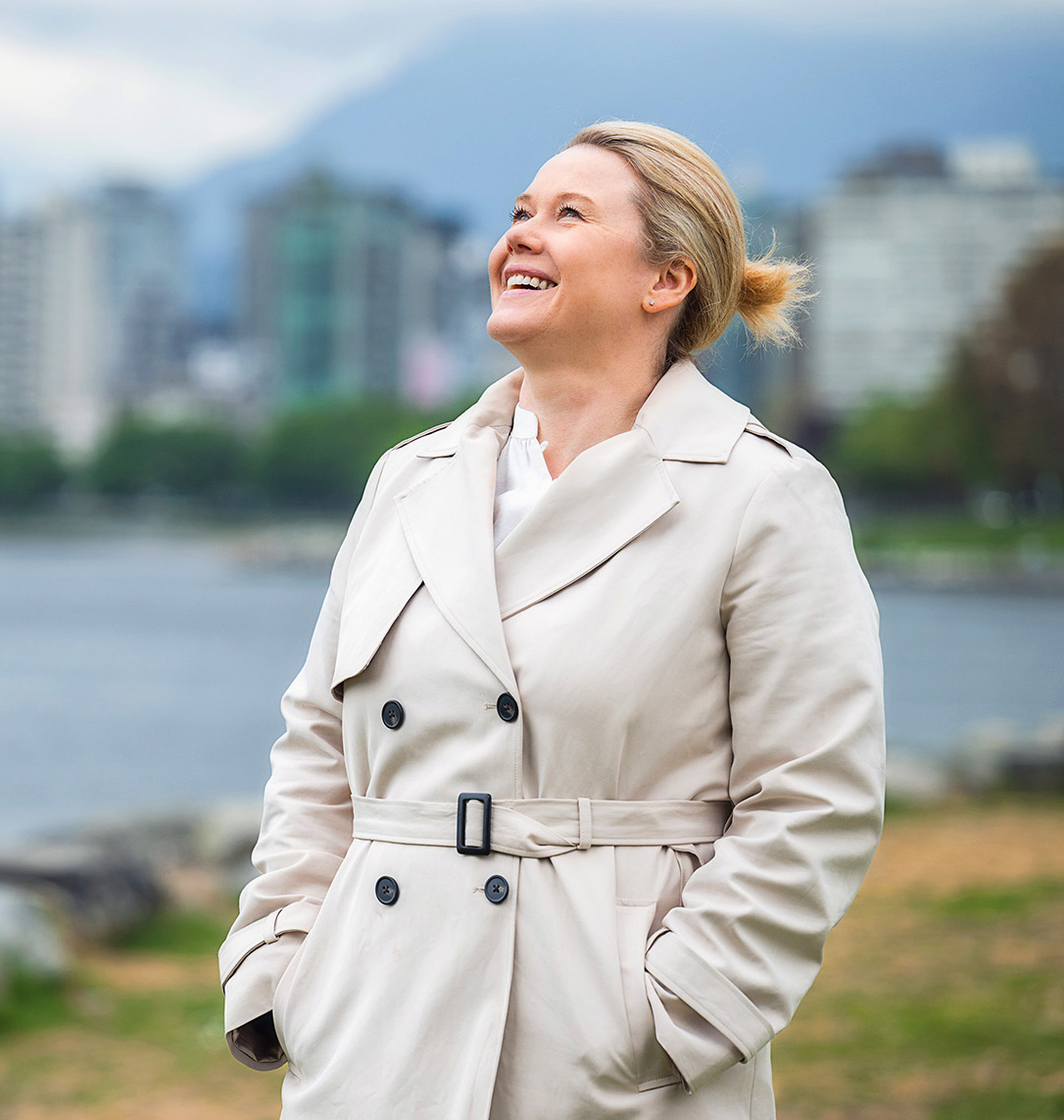 A woman wearing a trench coat takes in her surroundings in British Columbia, Canada.