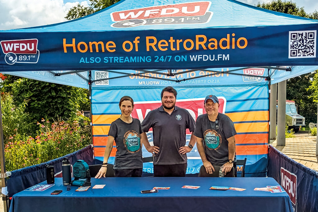 Three people stand under a tent at an event.