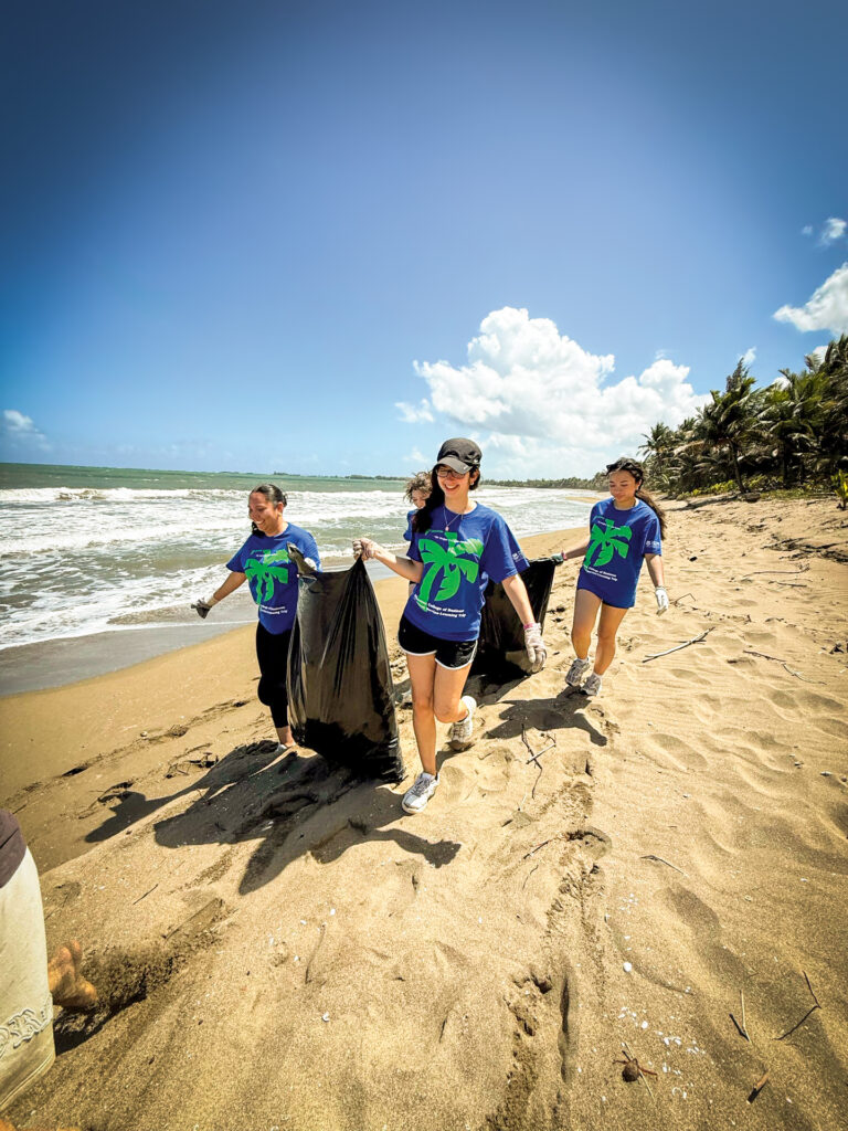 Four women clean up a beach and remove trash.
