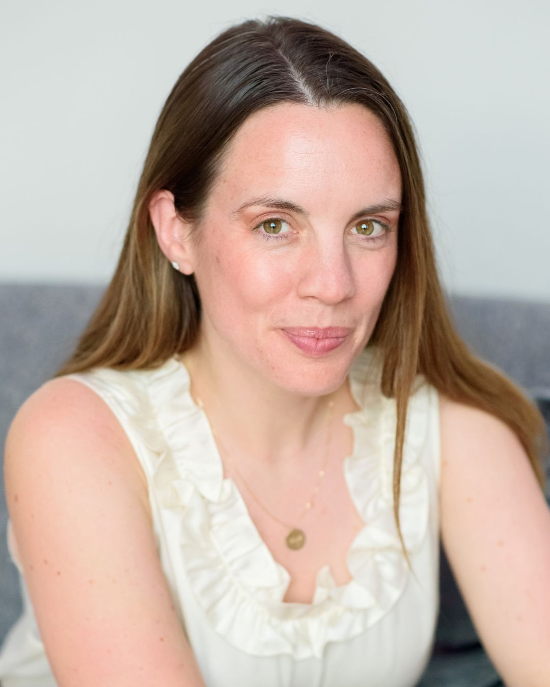 a headshot of a woman. she wears a white blouse.