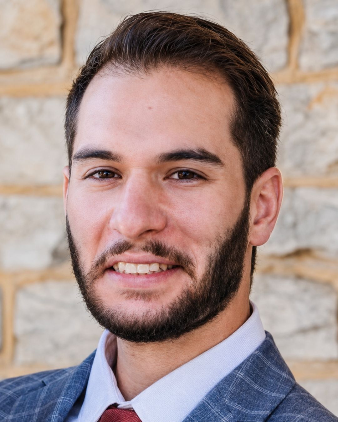 a headshot of a man. he wears a suit and tie.