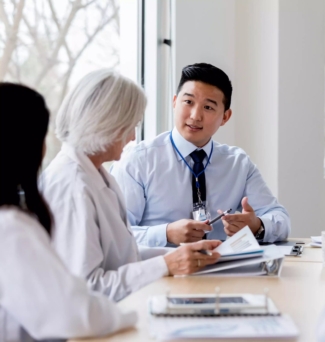 Mid adult male hospital administrator gestures while discussing hospital business with a female doctor during a staff meeting.
