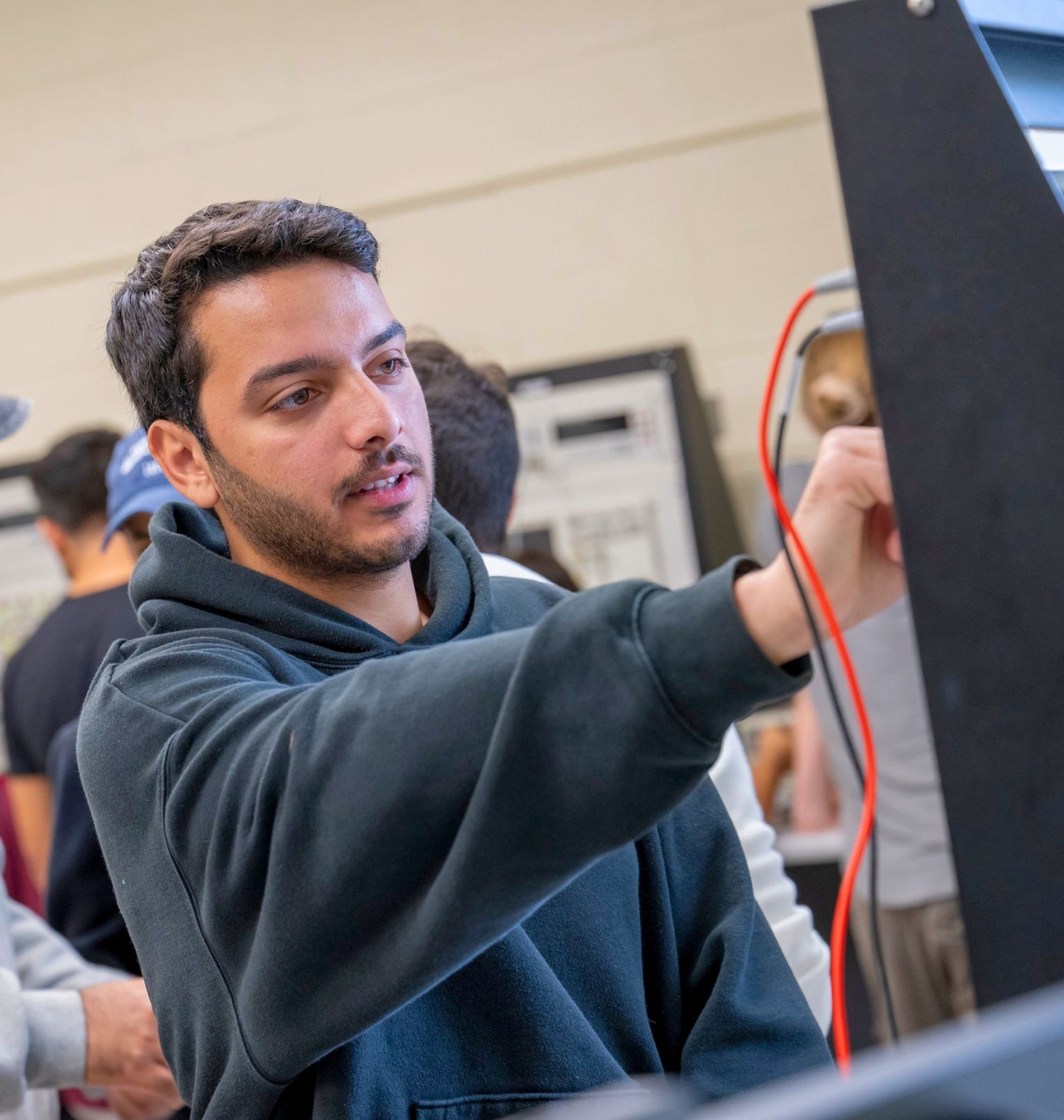 a college student works on wires in a computer.