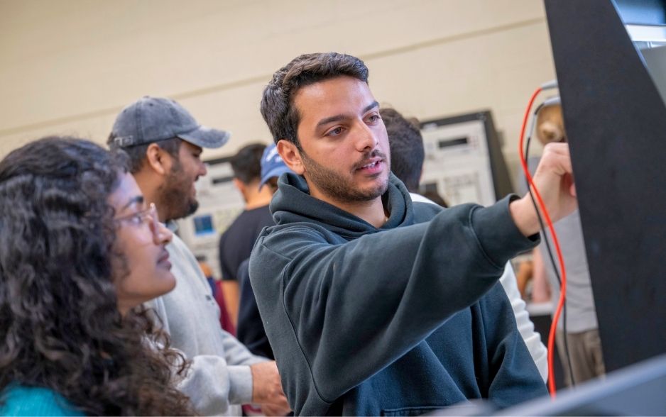 a college student works on wires in a computer.