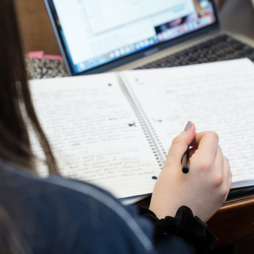 An open notebook and a woman's hand writing.